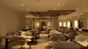 A spacious restaurant with multiple tables and chairs, a central dining area, and a decorative archway.