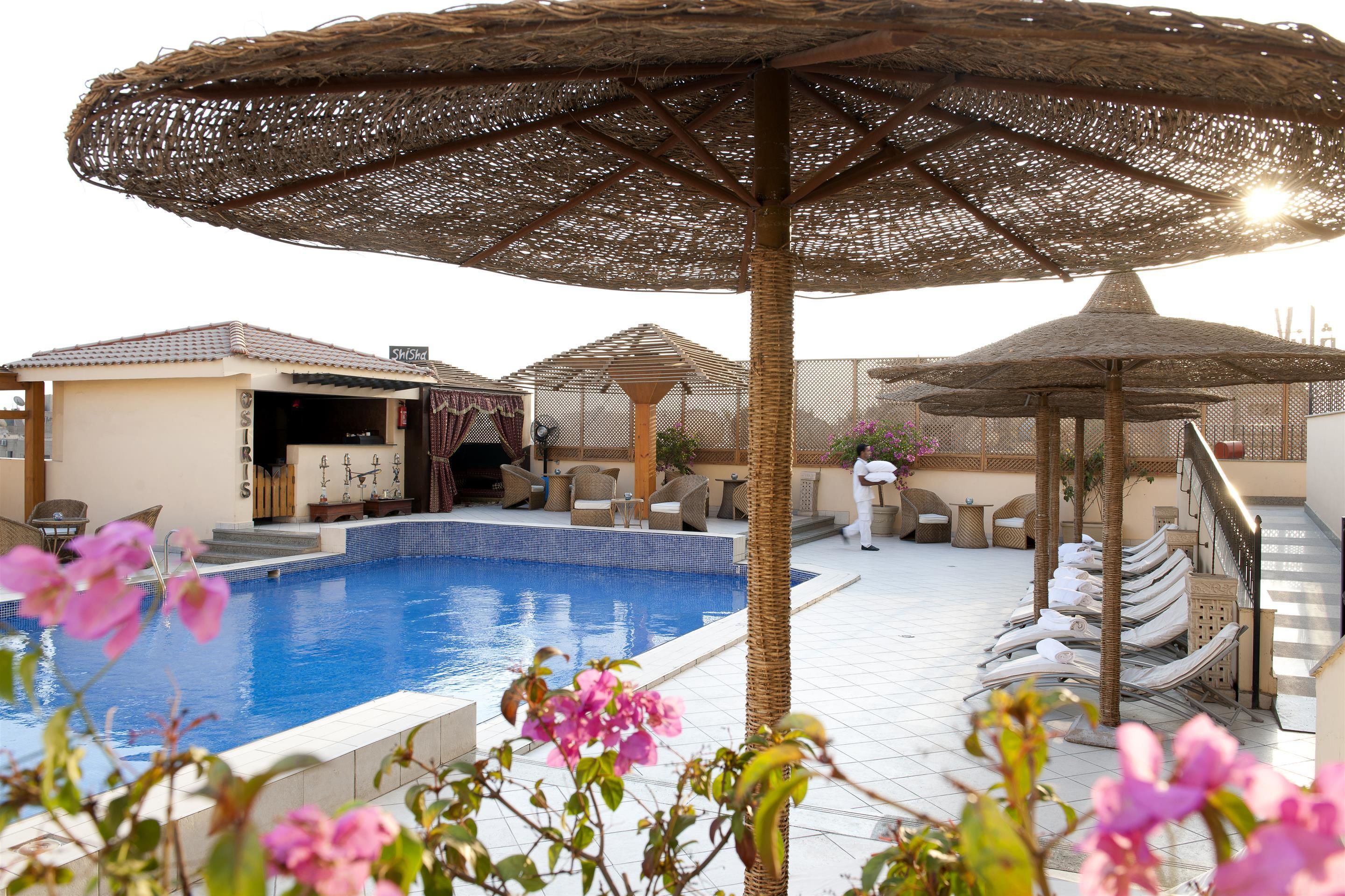 Una piscina al aire libre, sombrillas, sillones reclinables de piscina