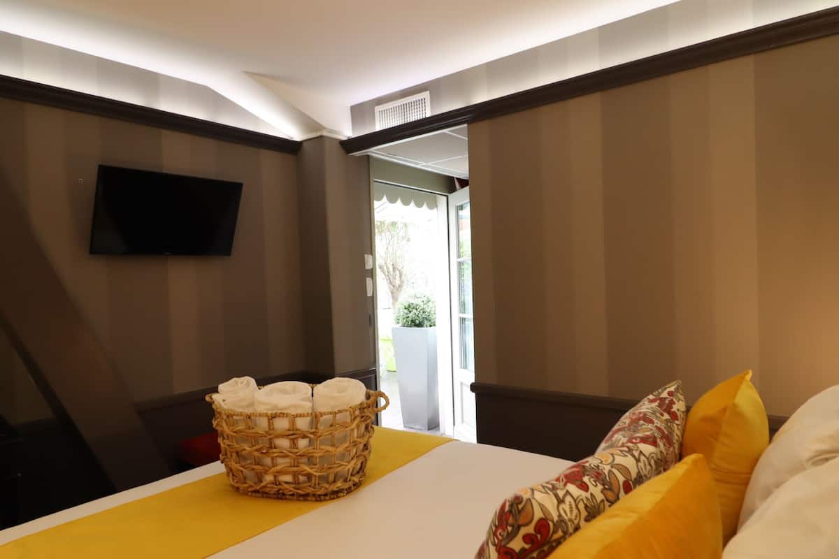Una camera d'albergo con un letto, una televisione a parete, un cesto di vimini con asciugamani e vista sull'esterno.