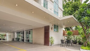 A modern building with a covered entrance, outdoor seating area, and potted plants. - iCheck inn Residence soi 2 (Bangkok)