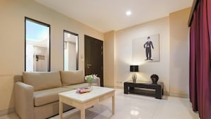 A modern living room with a beige sofa, a white coffee table, and a black side table with a lamp. - iCheck inn Residence soi 2 (Bangkok)