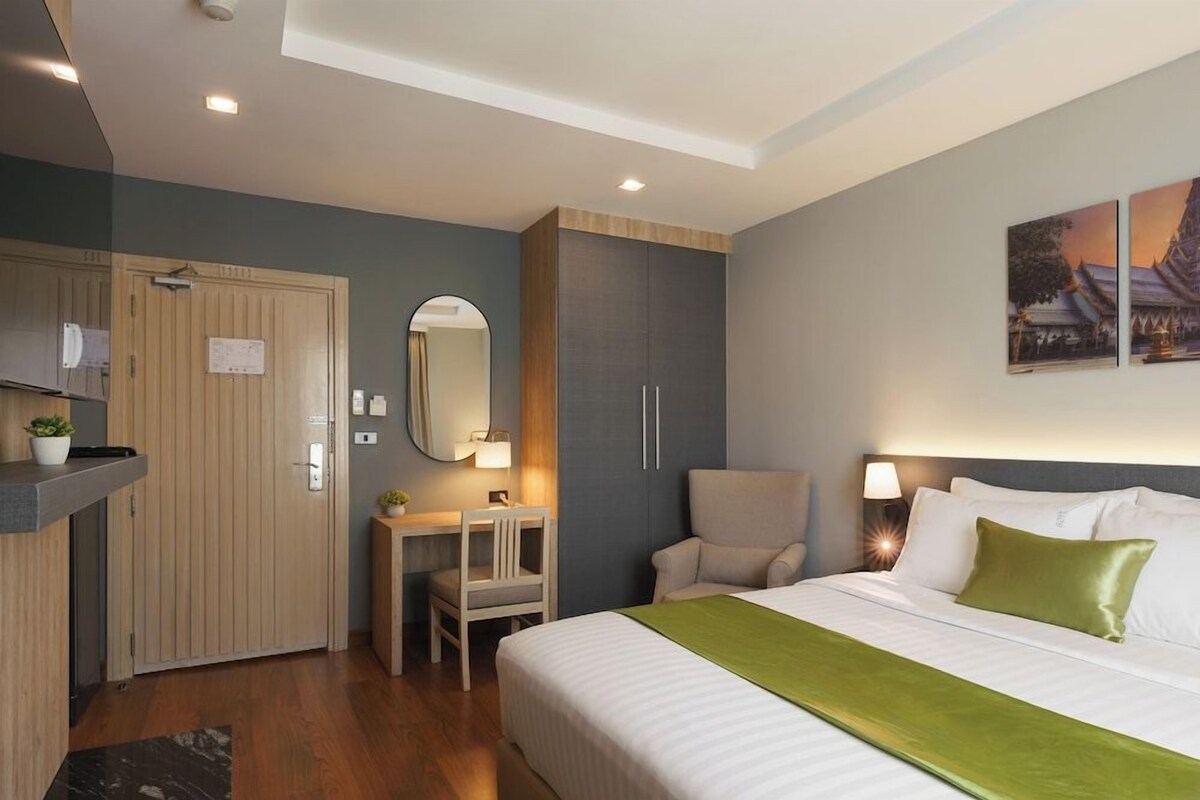Ein Hotelzimmer mit Bett, Schreibtisch, Stuhl, Kleiderschrank und Spiegel.