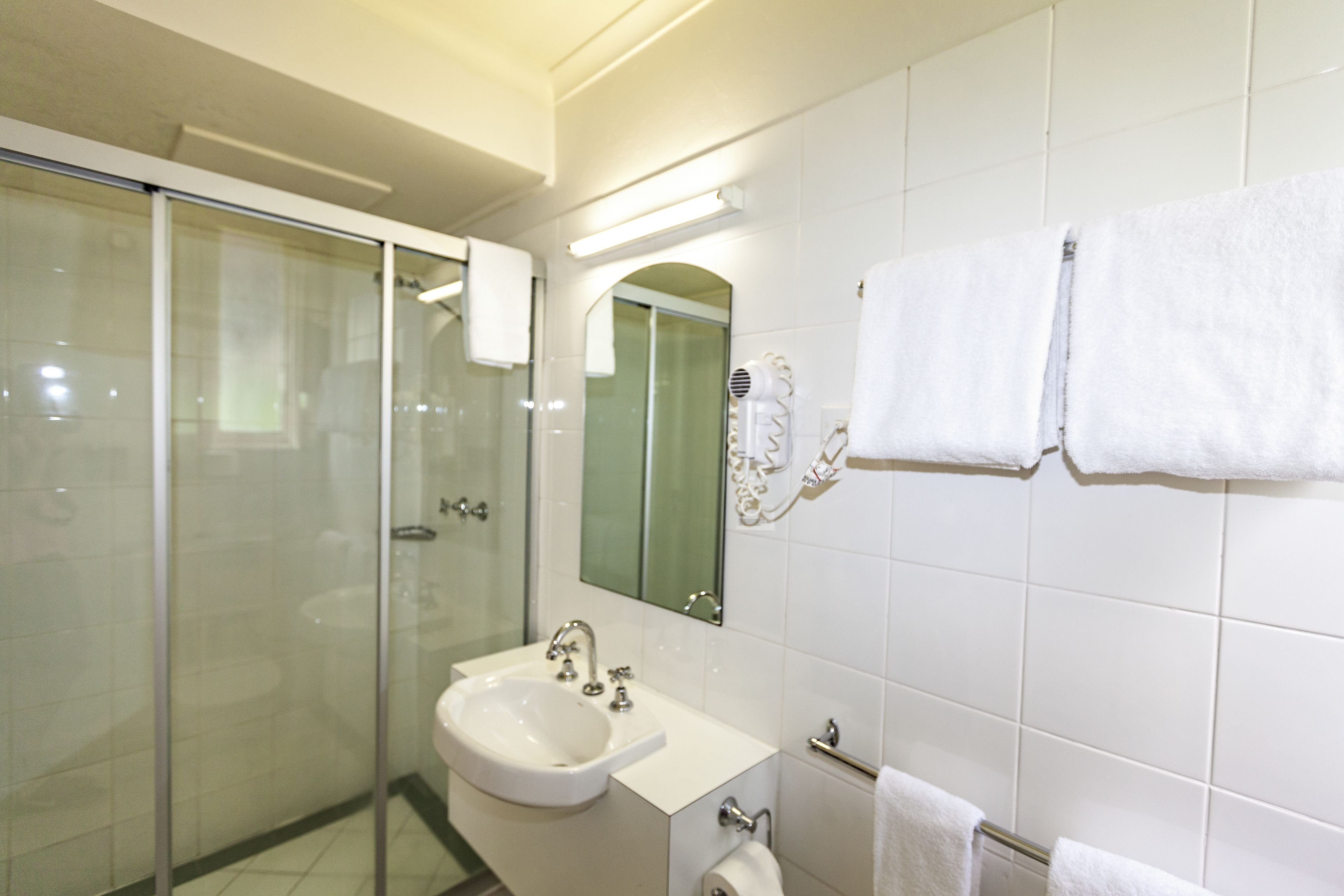 Un baño moderno con cabina de ducha de vidrio, un lavabo blanco y un espejo encima.