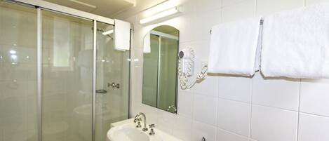 Een moderne badkamer met een douchecabine van glas, een witte wastafel en een spiegel erboven.