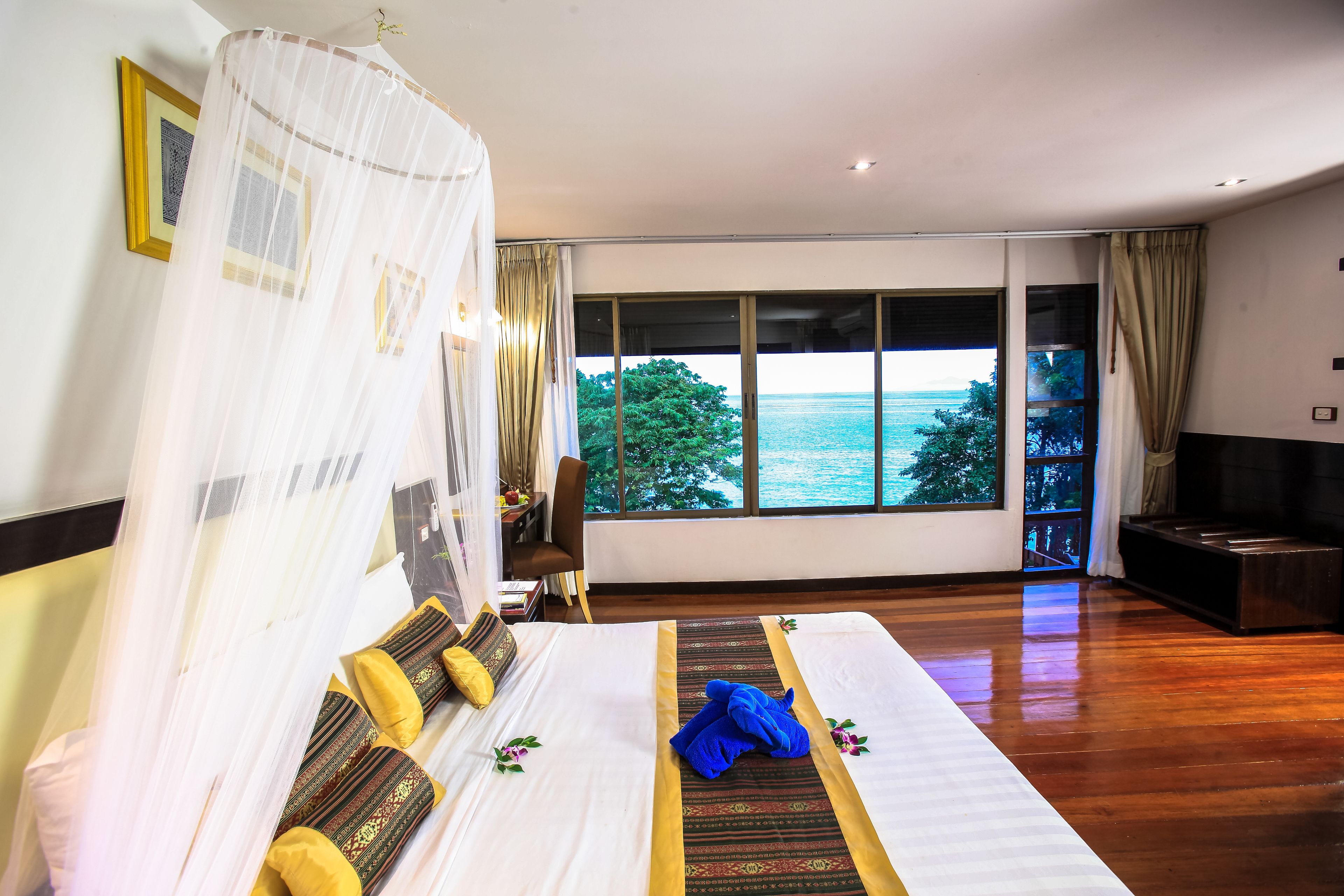 A spacious bedroom with a large bed, a canopy, and a view of the sea.