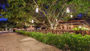 A pathway lined with lush greenery and wooden fences, leading to a building with traditional architecture and hanging lanterns. - Phi Phi Natural Resort (Ko Phi Phi)
