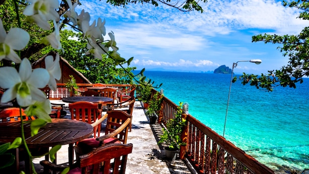 A seaside restaurant with outdoor seating, a view of the ocean, and a wooden deck. - Phi Phi Natural Resort (Ko Phi Phi)
