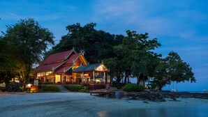 A beachfront hotel with a red roof and a covered porch. - Phi Phi Natural Resort (Ko Phi Phi)