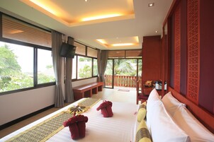 A hotel room with a large bed, a bench, a balcony, and a TV.
