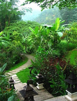 Un jardín exuberante con un sendero de piedra y faroles tradicionales.