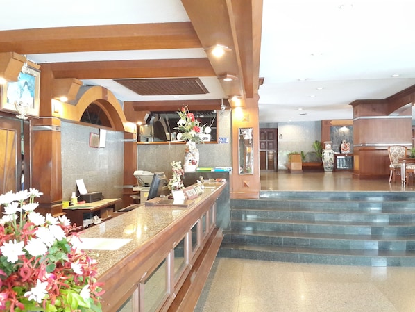 A reception area with a counter, a desk, and a staircase leading to an upper floor. - Caesar Palace Hotel (Pattaya)