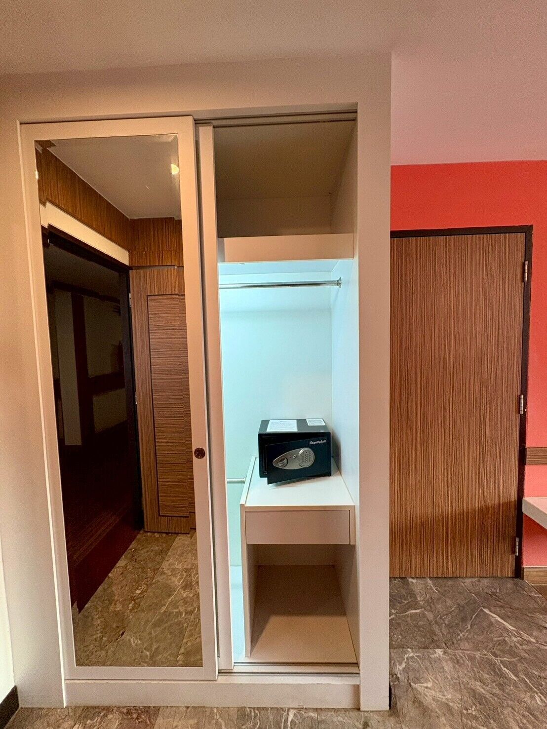 A room with a sliding door closet, a small white shelf, and a wooden door.