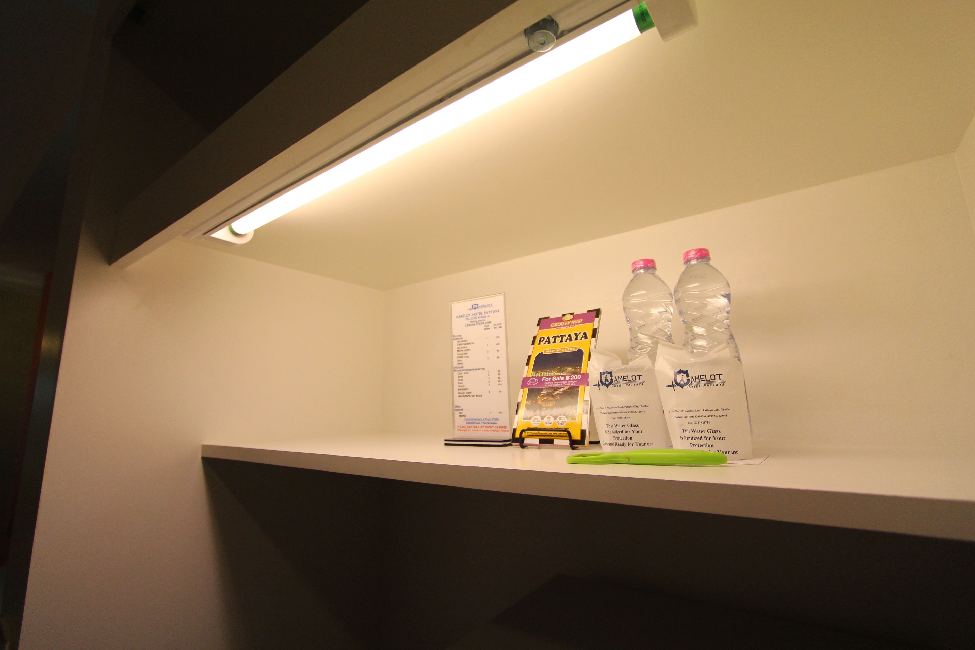 A shelf with bottled water, a water glass, and a promotional sign.