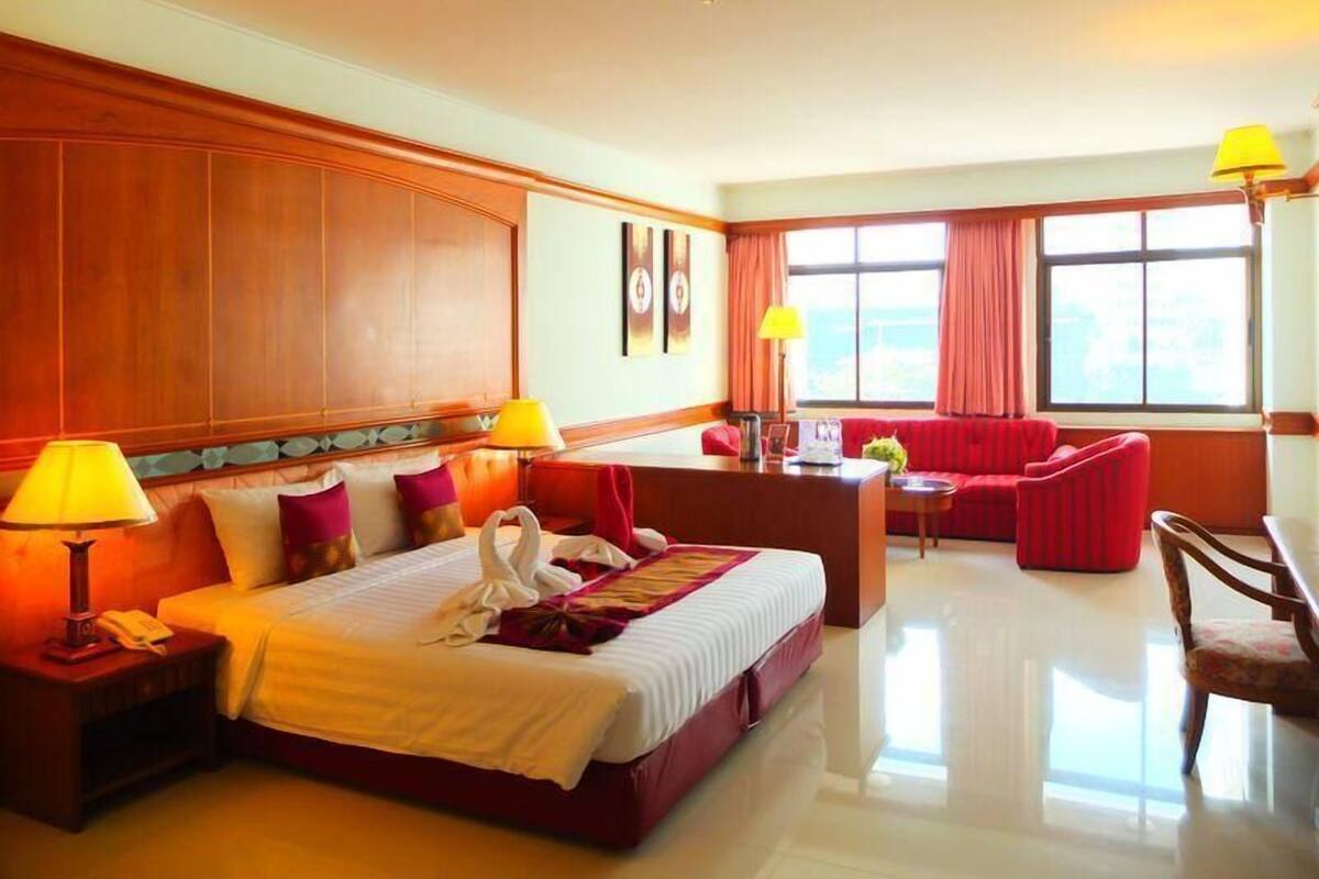 Una habitación de hotel con una cama grande, un escritorio, un sofá rojo y una silla.