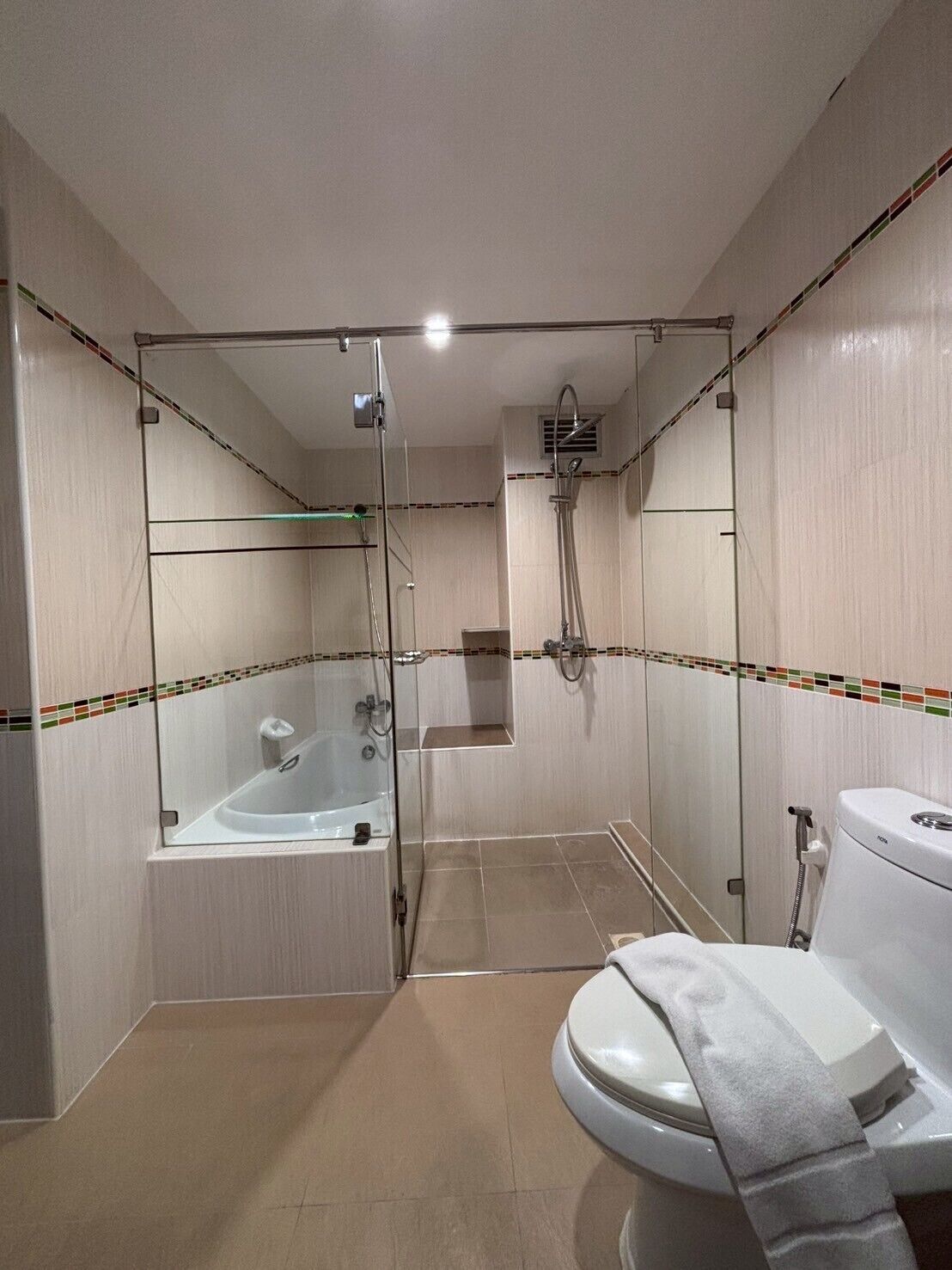 Een moderne badkamer met een glazen douchecabine, een badkuip en een toilet.