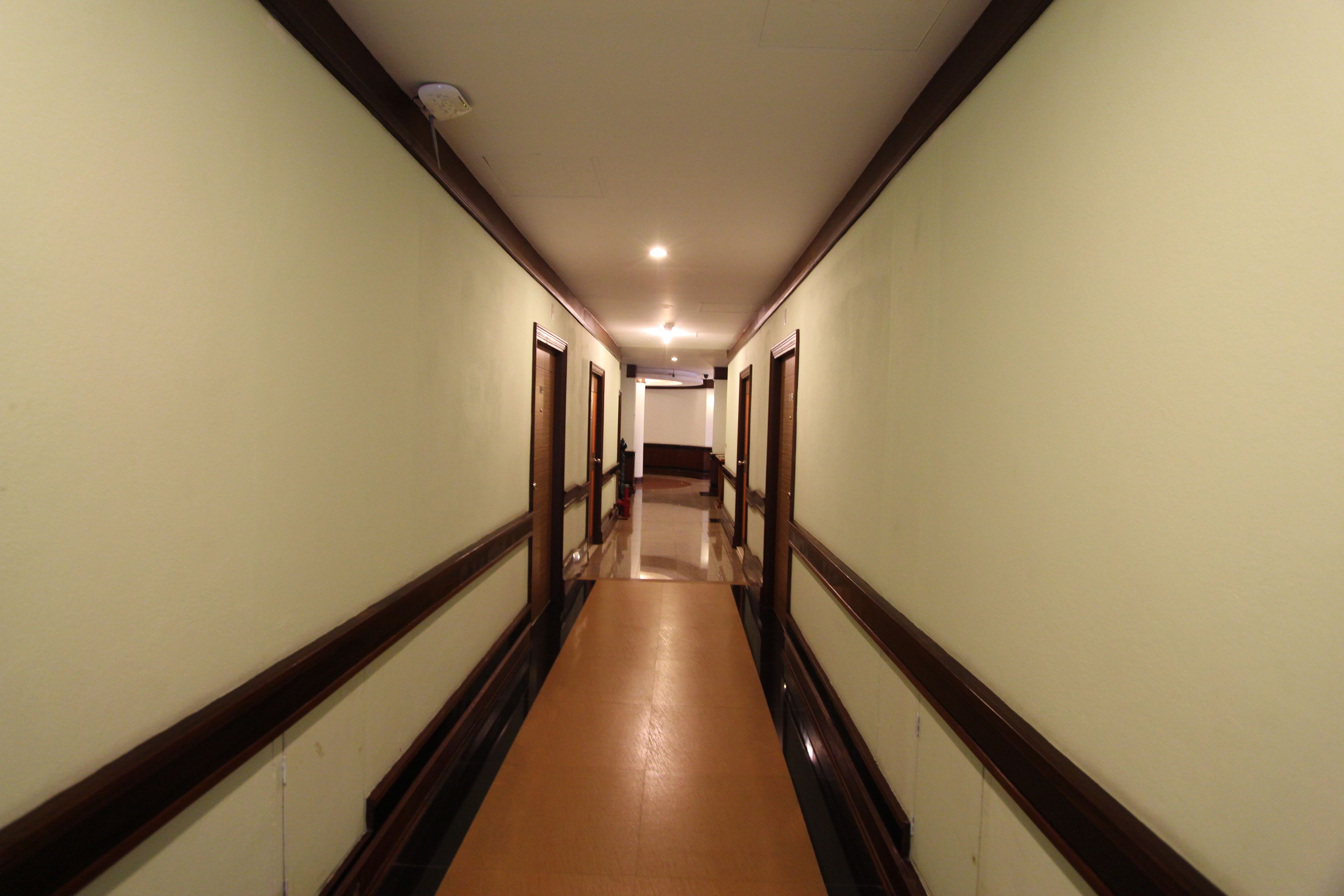 A long, narrow hallway with wooden trim and a polished floor, leading to a door at the end.