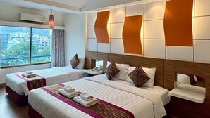 A hotel room with two beds, a large window, and a city view. - Camelot Hotel Pattaya (Pattaya)