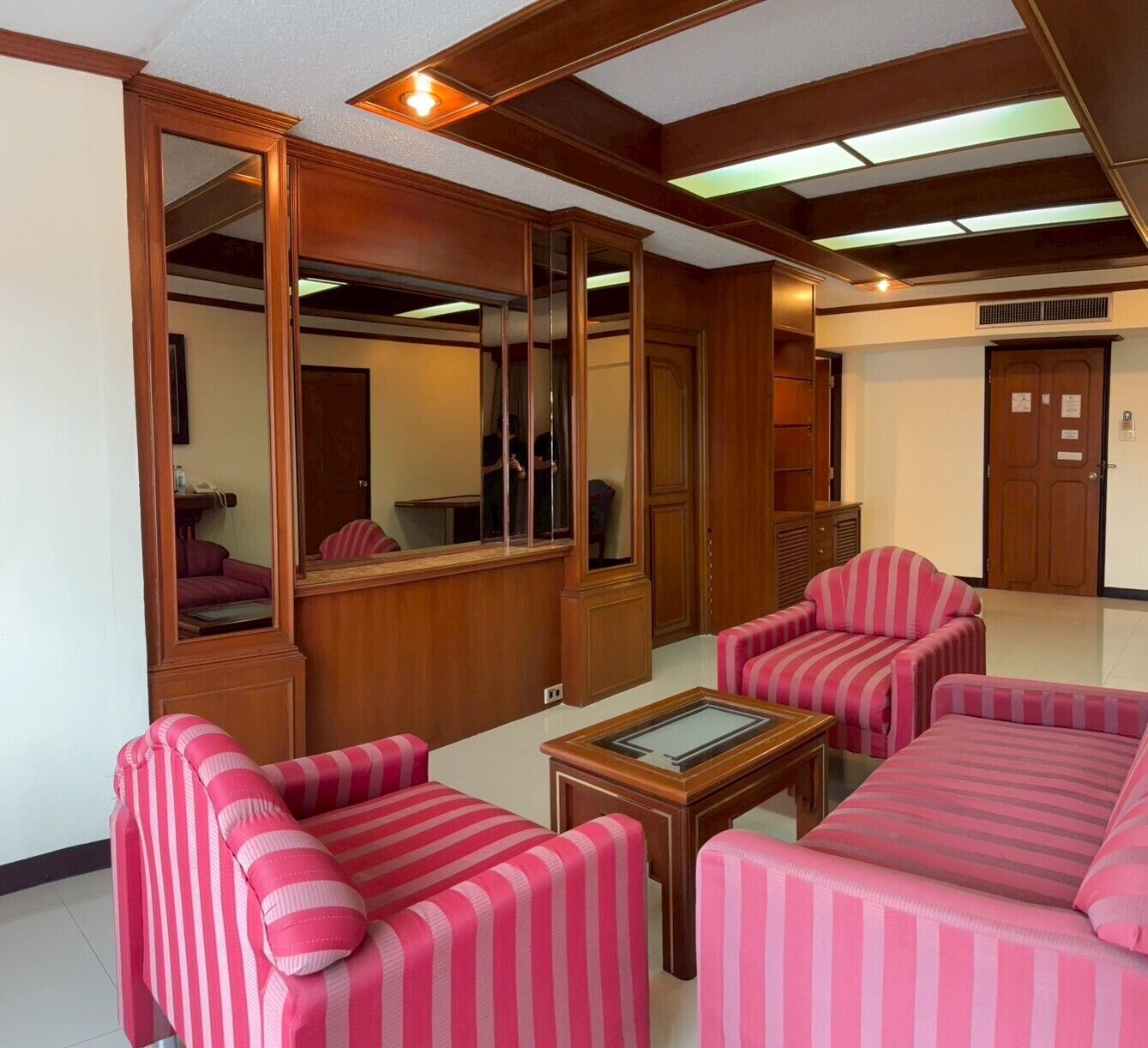 A room with striped sofas, a wooden coffee table, and a large mirror.