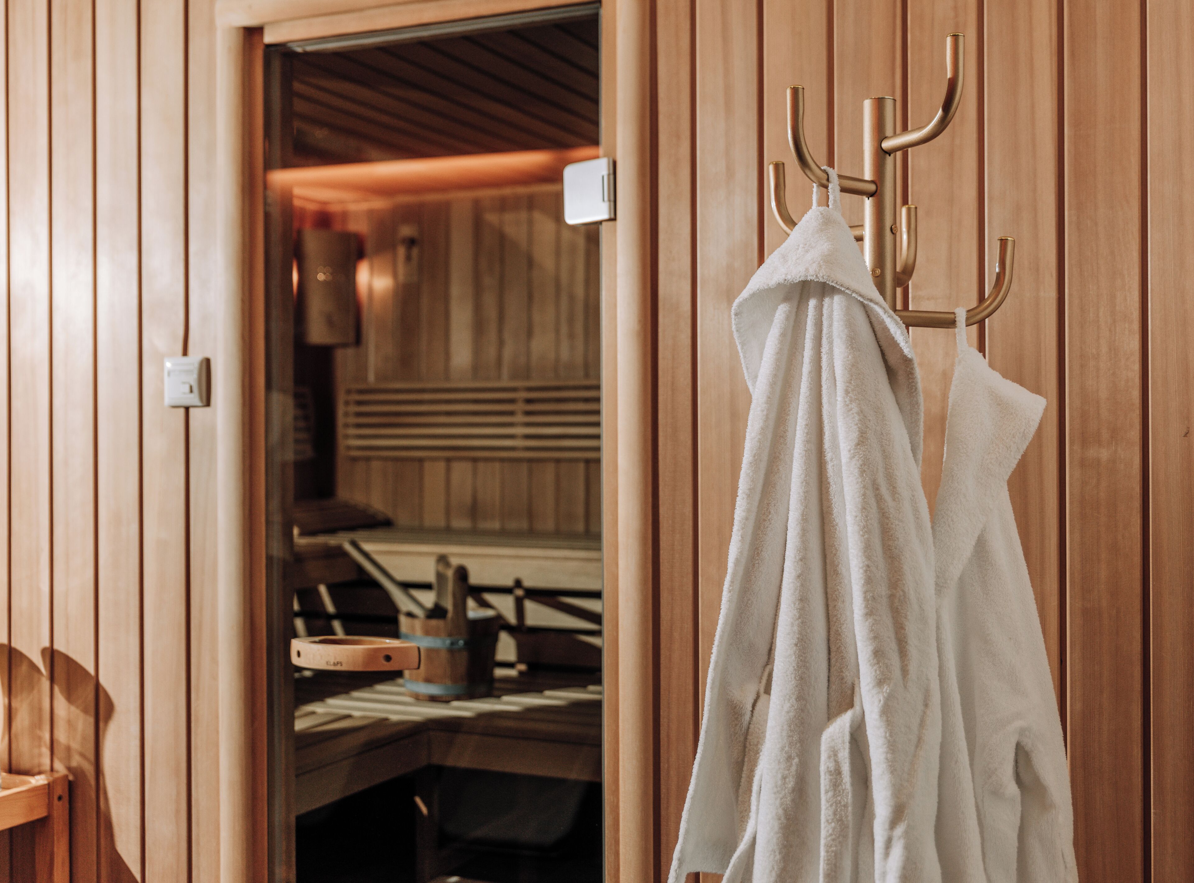 Interior de madeira com porta-toalhas e área de sauna.