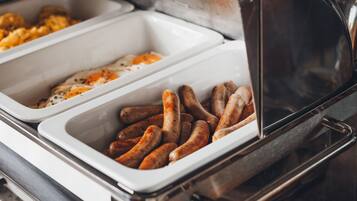 A buffet with two trays, one containing scrambled eggs and the other with sausages.
