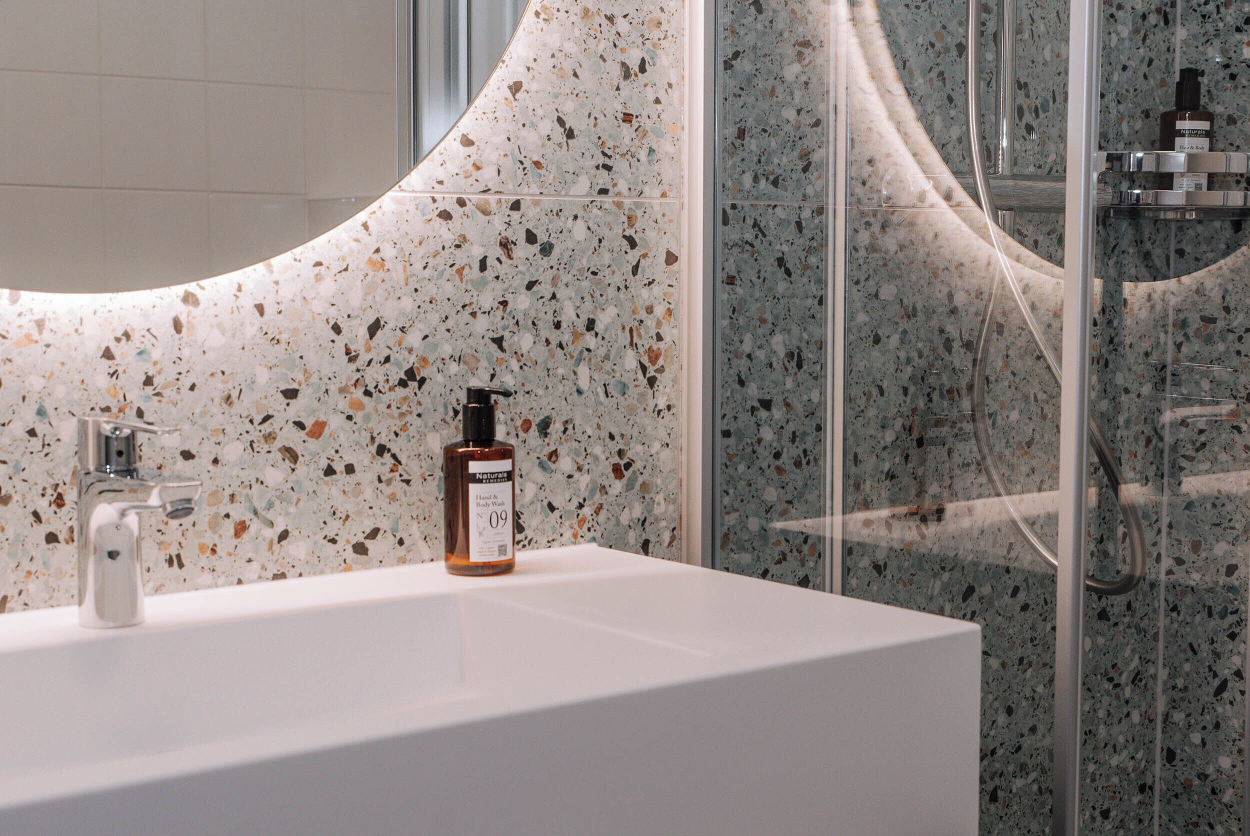 A bathroom with a white sink, a mirror, and a shower area with a glass door.