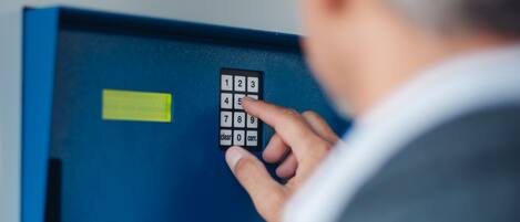 A person using a blue secure access panel with a keypad and a yellow label.