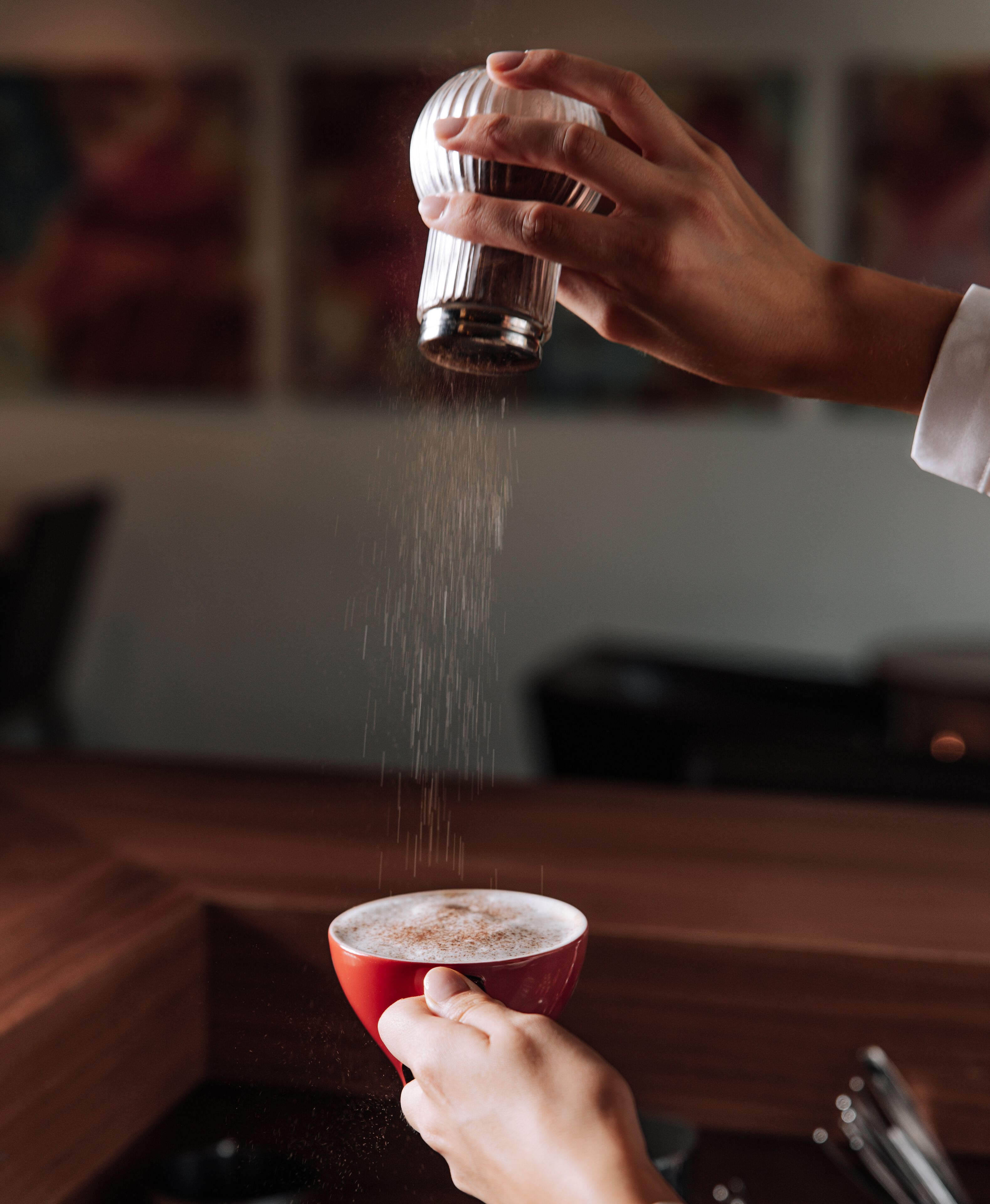 Una persona sirviendo una bebida en un vaso rojo.