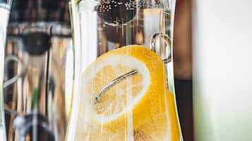 A clear glass container with a lemon slice and a metal straw inside.