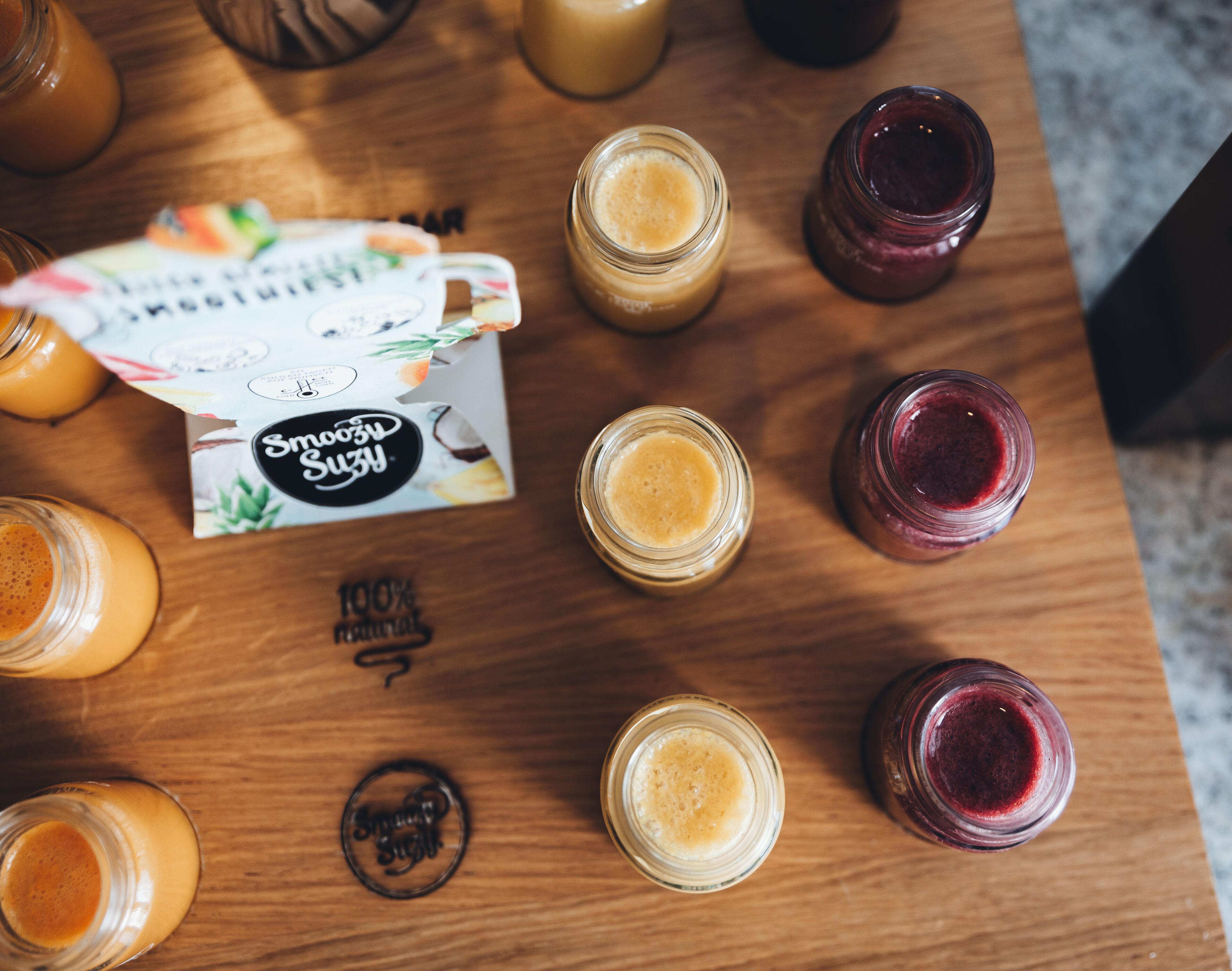 Una mesa de madera con varios frascos de batido y una tarjeta.