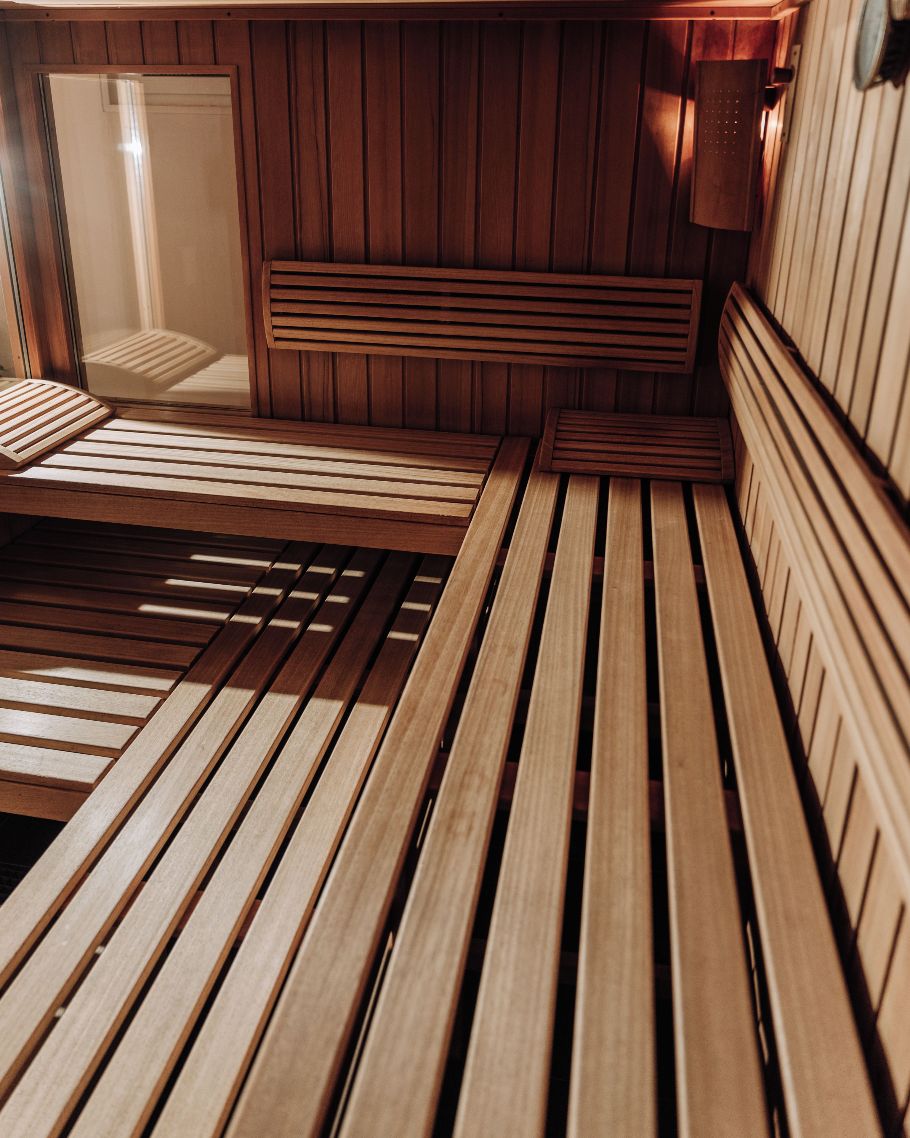 Una sauna de madera con bancos y un banco en primer plano.