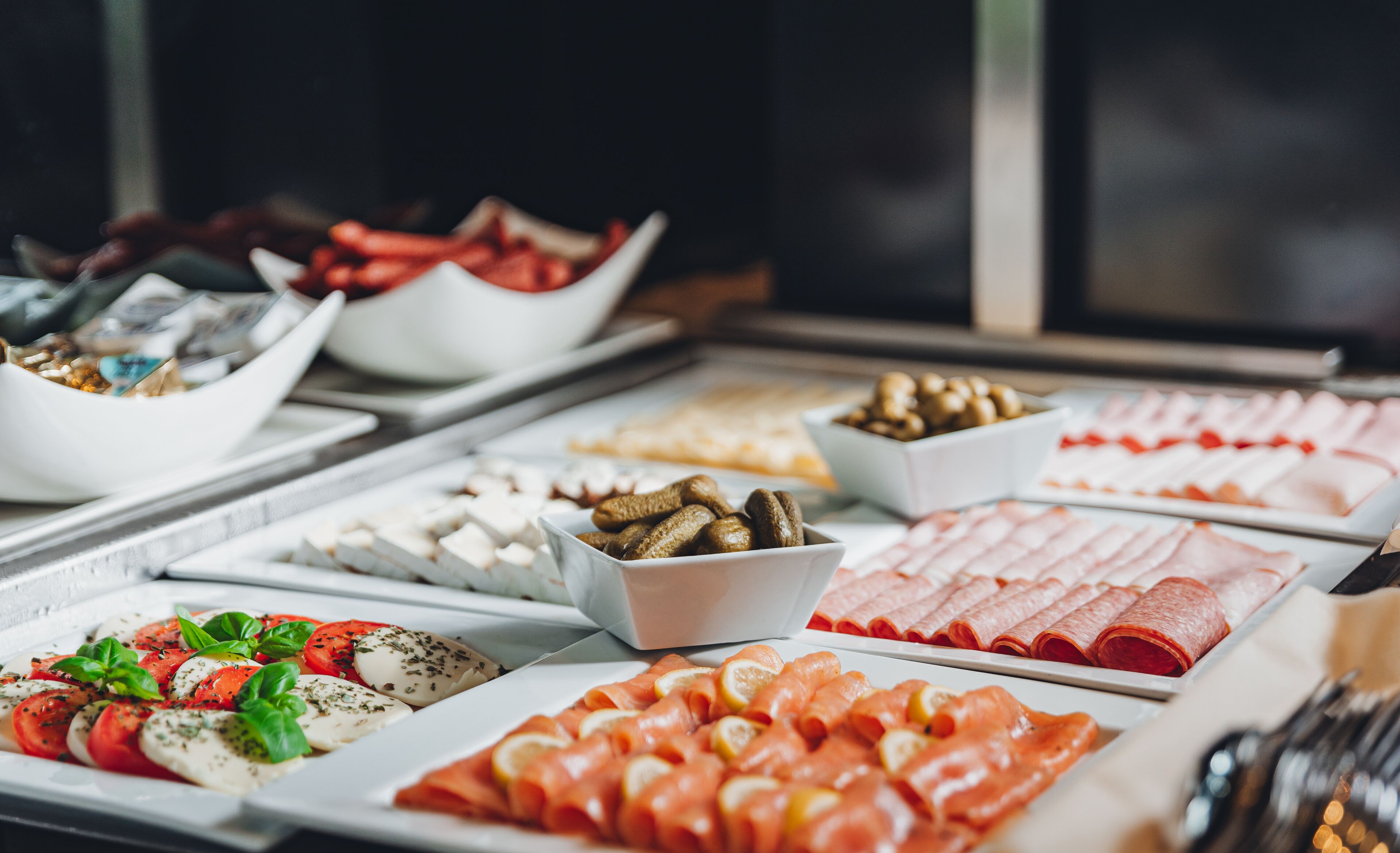 A buffet with various food items including sliced meats, cheeses, and vegetables.