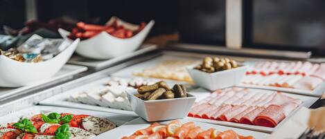 A buffet with various food items including sliced meats, cheeses, and vegetables.