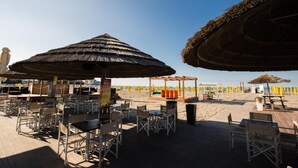 A beachside restaurant with outdoor seating, thatched umbrellas, and a wooden deck. - Laguna Palace Hotel (Grado)