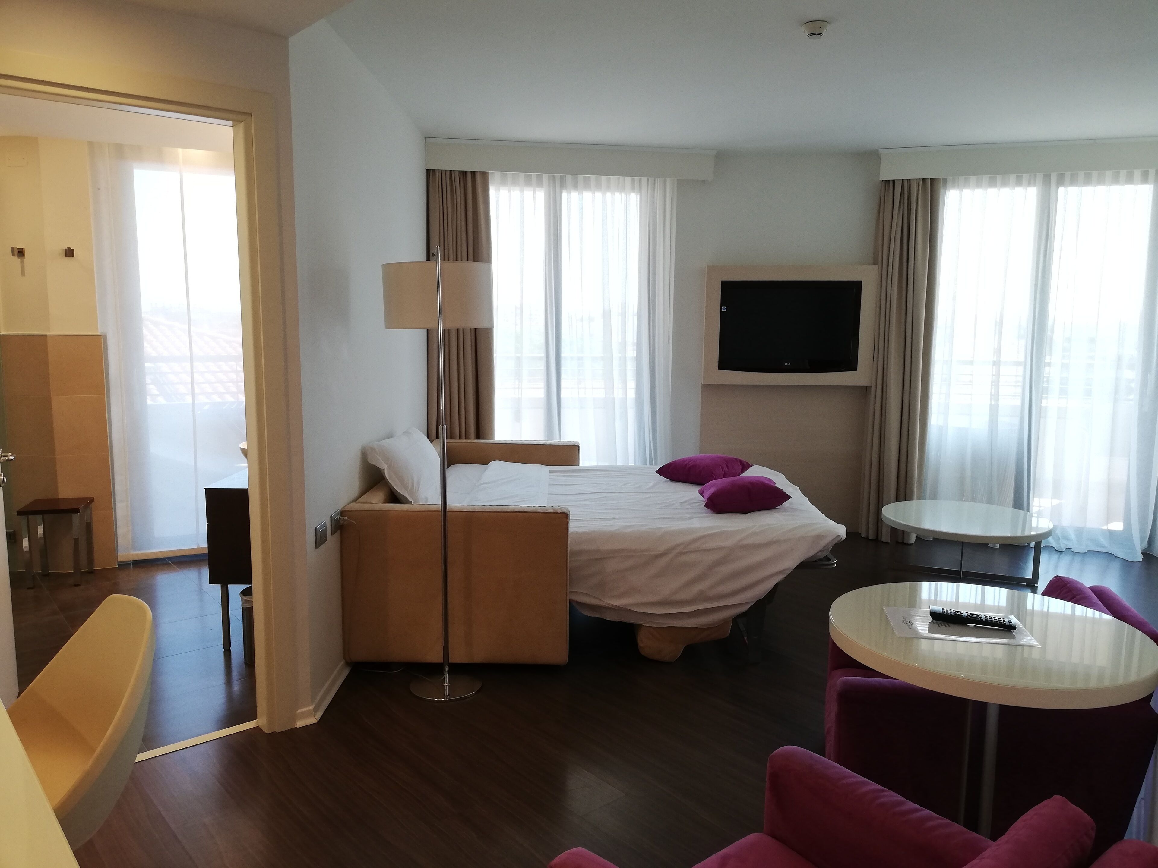 Una habitación de hotel con cama, televisor, una mesita y una silla.