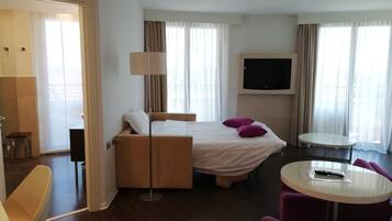 Una habitación de hotel con cama, televisor, una mesita y una silla.