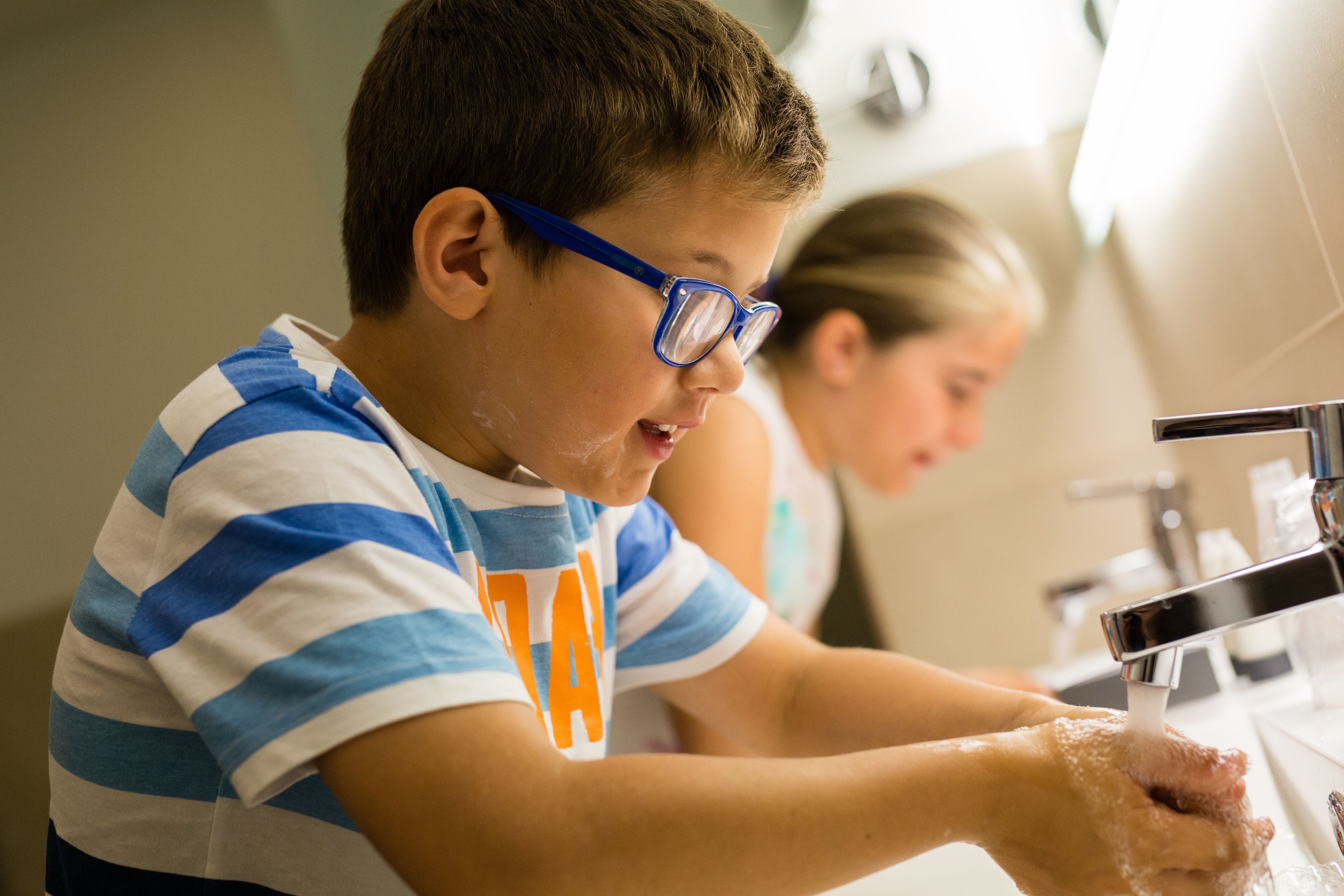 A child washing hands at a sink.