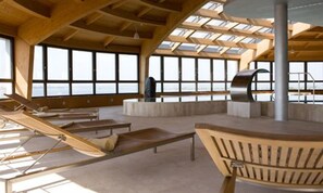 A spacious indoor area with large windows, wooden furniture, and a central column.