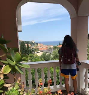 A balcony with a view of a coastal town and the sea.