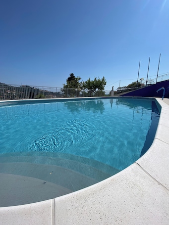 Una piscina al aire libre de temporada, sombrillas