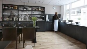 Ett modernt kök med mörka skåp, en bardisk och en matplats.