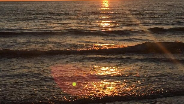 En solnedgång över havet, där solljuset speglas i vattnet.