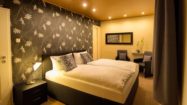 Un dormitorio con cama, mesitas de noche, escritorio y una silla.
