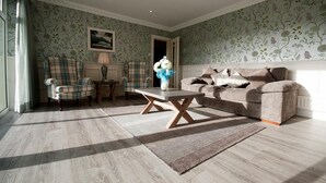 A living room with a sofa, chairs, a coffee table, and a lamp. - Castle Lodge (Killarney)