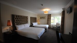 A hotel room with two beds, a desk, a chair, and a television on the wall. - Castle Lodge (Killarney)