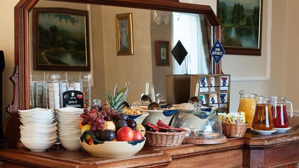 A buffet counter with various food items, including fruits, cereals, and beverages. - Castle Lodge (Killarney)