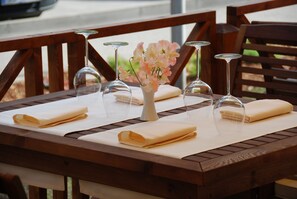 A wooden table set with folded napkins, wine glasses, and a vase with flowers.
