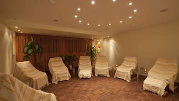 A room with six striped chairs arranged in a semi-circle, a wooden parquet floor, and several potted plants.