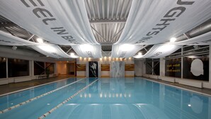 Une grande piscine intérieure avec des couloirs clairement délimités et des banderoles suspendues au plafond.