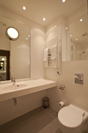 A modern bathroom with a large mirror, a sink, a toilet, and a towel rack.