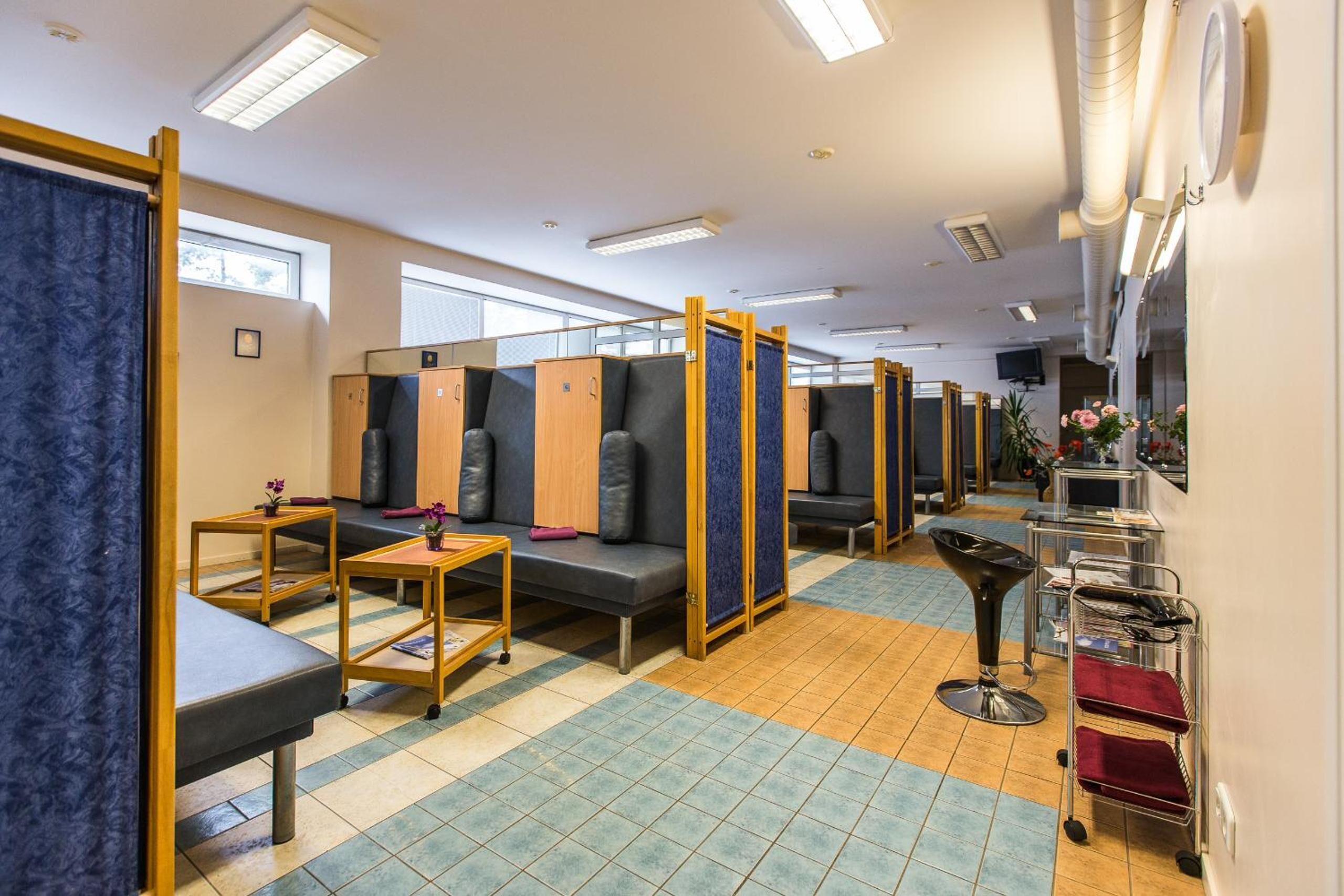 A hotel room with a checkered floor, multiple seating areas, a TV, and a cart with items.